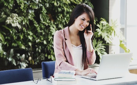 Frau mit Telefon und Laptop am Schreibtisch